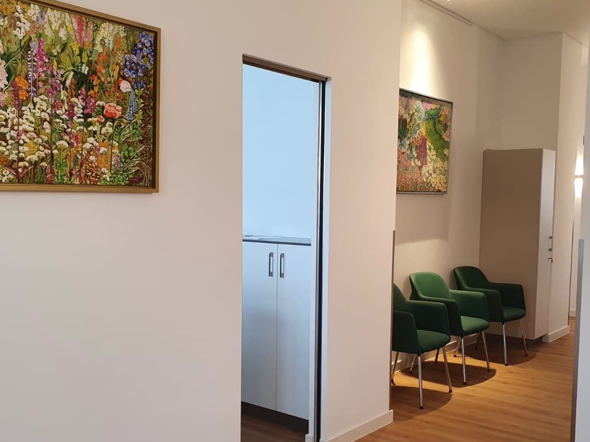 Kleiner Vorwartebereich mit grünen Sesseln und zwei Wandbildern